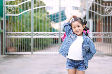 Fototapeta premium Asian children or kid girl smile and student holding and show pink schoolbag with happy fun because go to school or back to school and kindergarten from summer study or learning to home and wear jeans