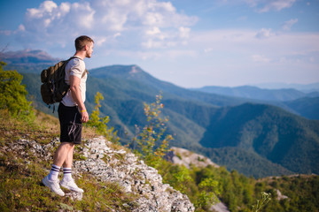 Naklejka na ściany i meble Breathing the fresh mountain air. Young man at the summit enjoying the view.