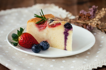 Mixed berry butter cake with fresh blueberries and strawberries on white plate put on wood table in side view copy space. Delicious and moist with sweet and sour taste in homemade bakery concept.