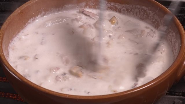 Seafood chowder boiling in a clay pan in UHD