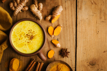 Hot turmeric milk with spices on wooden table