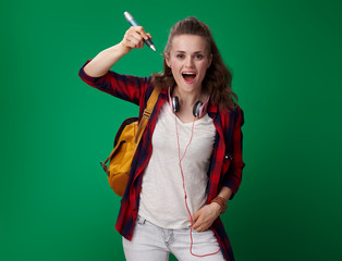 student woman writing in air with big pen on green background