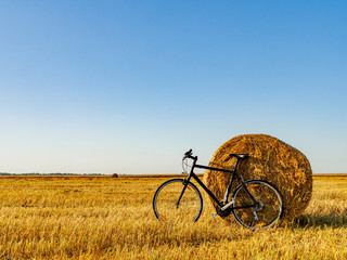 Bicycle in the field with big round bales of straw