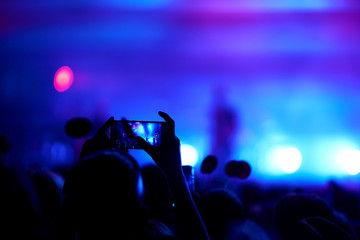 Use advanced mobile recording, fun concerts and beautiful lighting, Candid image of crowd at rock concert, Close up of recording video with smartphone, Enjoy the use of mobile photography.