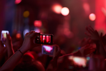 Use advanced mobile recording, fun concerts and beautiful lighting, Candid image of crowd at rock concert, Close up of recording video with smartphone, Enjoy the use of mobile photography.