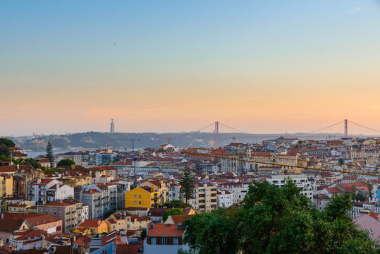 Lisbon, Portugal Old Town Skyline With View On River Tagus And Bridge On Sunset