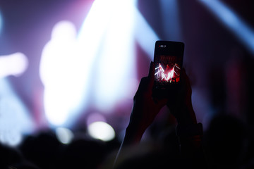 Use advanced mobile recording, fun concerts and beautiful lighting, Candid image of crowd at rock concert, Close up of recording video with smartphone, Enjoy the use of mobile photography.