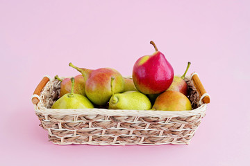 Group of rape pears in basket on pale pink background