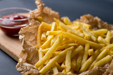 fried potatoes on wrapping paper with ketchup