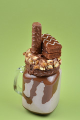 Chocolate extreme milkshake with brownie cake, chocolate paste and sweets. Crazy freakshake food trend. Copy space
