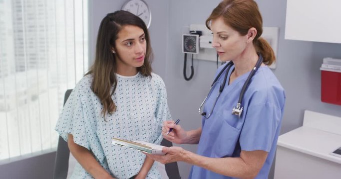 Portrait of hispanic woman going over health history with senior nurse