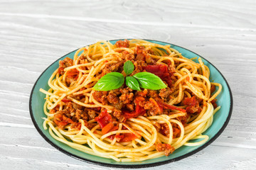 Spaghetti bolognese on a blue plate on white wooden table. healthy food. close up