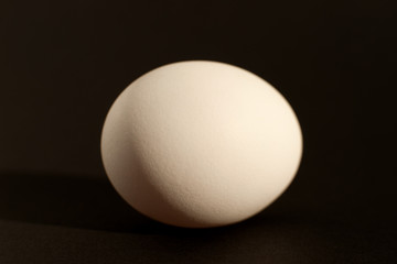 Egg on a black background. Macro. Chicken egg in the form of a sphere on a black background. Isolate. Chicken egg closeup.