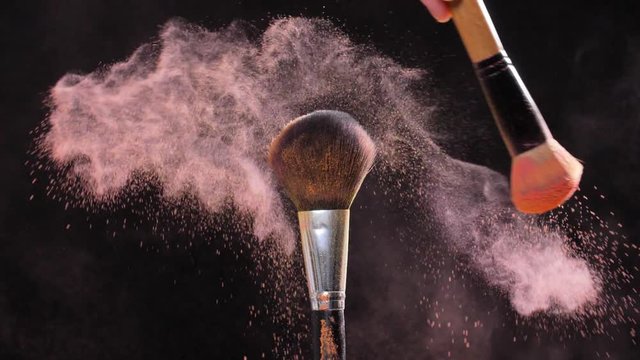 Two Make-up brush with pink powder on black background