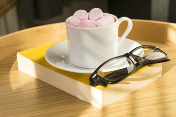 Hot chocolate with marshmallows and book, glasses