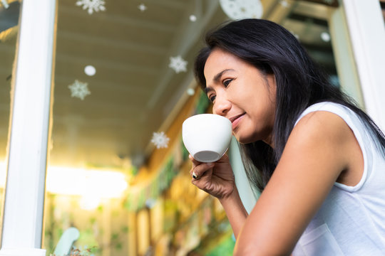 Happy asian woman drinking coffee in cafe