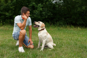 Friendship of man and dog. Happy young man sitting with his friend - dog Labrador
