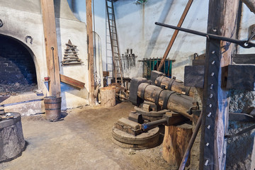 Interior of the old mediaeval vintage water powered blacksmith workshop or forge with hammer, anvil, tools and furnace, old technology still working in Czech Republic.
