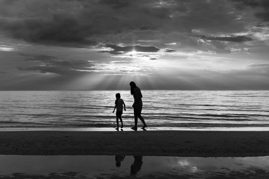 Mother and son relaxing on the beach at at sunset in black and white.