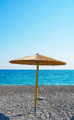 Umbrella on a pebbly beach in a hot sunny day at the resort. Beautiful blue sea and clear sky