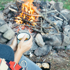 woman sitting near fire with cup of tea