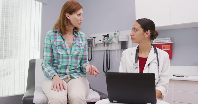 Portrait of white senior patient talking to young medical doctor about health