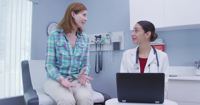 Young latina doctor taking notes of patients health on notebook computer