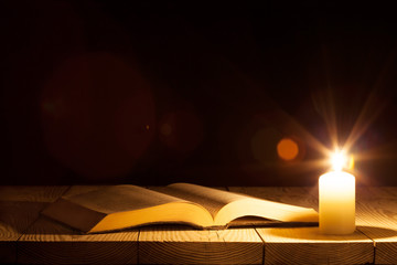 Obraz premium a bible on the table in the light of a candle