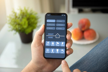 A man hands holding phone with app smart house in room home