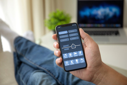 man on sofa holding phone with app smart home screen