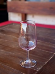 Close-up of an empty red wine glass on a wooden tabletop at an alpine restaurant. Vertical orientation. Montreux, Switzerland. Travel and tourism.