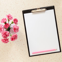 Photo of terrazzo desk with mockup of office pad, pink carnations in a vase and pink pencil