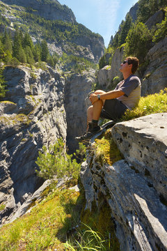 Resting tourist watching a deep limestone gorge Gletscherschlucht nearby resort of Grindelwald, Switzerland