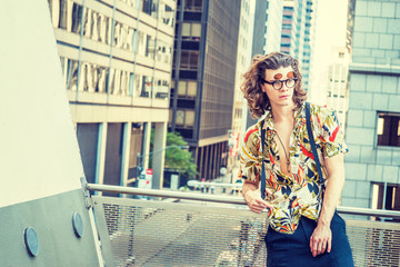 Obraz na płótnie Canvas Young Hispanic American Man with long brown curly hair, wearing double lens sunglasses, colorful patterned short sleeve shirt, black baggy loose pants with suspenders, standing on balcony in New York