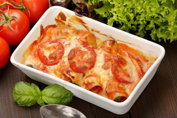 Caneloni stuffed with meat and melted cheese in white bowl over grunge wood background