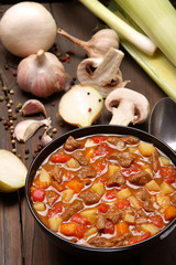 Beef stew in black bowl on wood background, top view goulash soup