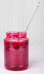 Glass jar with tasty currant jam on a table on tablecloth