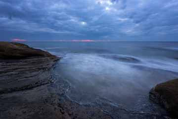 Seascape during sunrise. Beautiful natural seascape, blue hour. Sea sunrise at the Black Sea coast. Magnificent sunrise with clouds and fire sun in the middle of December.Ravda, Bulgaria