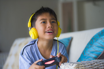 oung hispanic little kid excited and happy playing video game online with headphones holding controller enjoying having fun sitting on couch in child gaming addiction © TheVisualsYouNeed