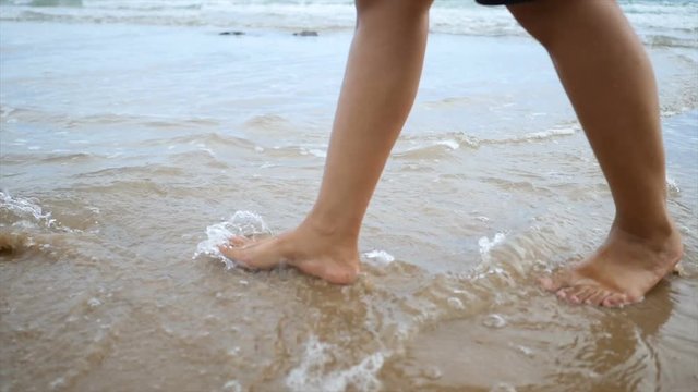 Slow motion woman feet walking on the sand beach with  nature sea wave coast for summer vacation concept