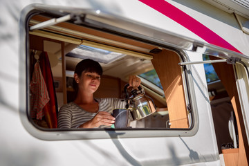 Woman cooking in camper, motorhome interior