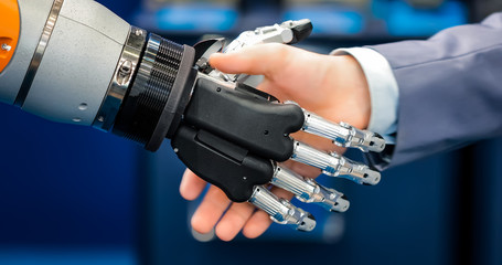 Hand of a businessman shaking hands with a droid robot. The concept of human interaction with...