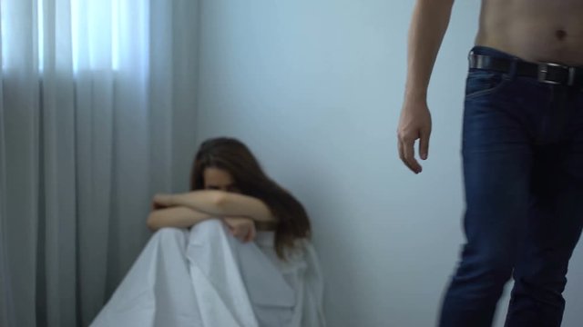 Man fastening belt on pants leaving frightened girl in corner, sexual abuse