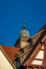 Fototapeta na wymiar Hölzerne Dachgauben in der Nürtinger Alleenstraße, dahinter der Turm der Stadtkirche St. Laurentius