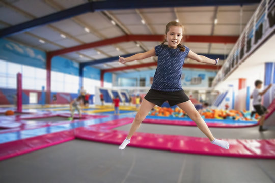 joyful little girl with pigtails and a smile on her face jumping on the trampoline