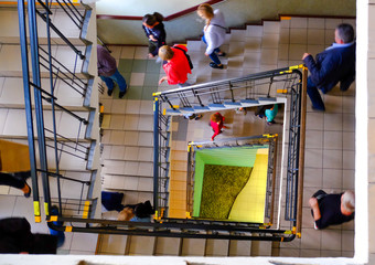 Square spiral staircase. top view of several people.