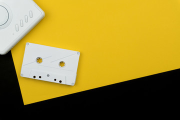 a white audio cassette tape with a white portable cassette player on the yellow and black background