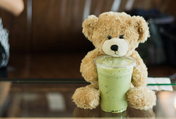 Matcha green tea juice on work table and teddy bear,selective focus.