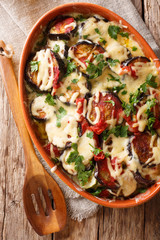 Baked aubergines with tomatoes and mozzarella cheese and parmesan close-up. Vertical top view