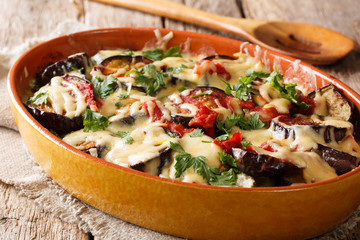 Traditional recipe for baked eggplants with tomatoes, herbs and cheese close-up. horizontal